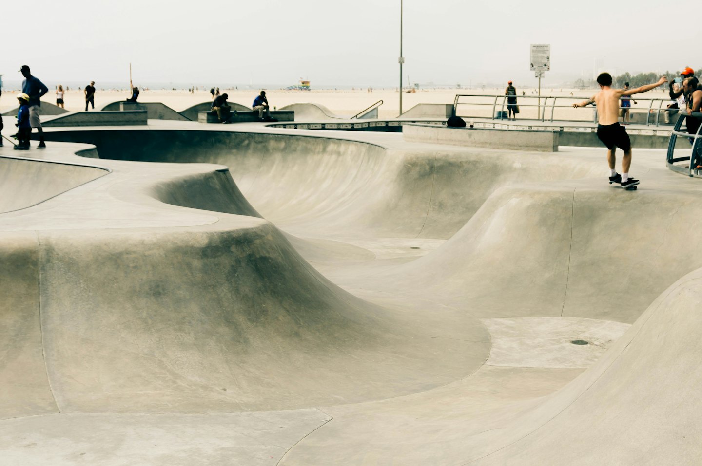 Un uomo in equilibrio su uno skateboard in uno skatepark con l'oceano sullo sfondo.