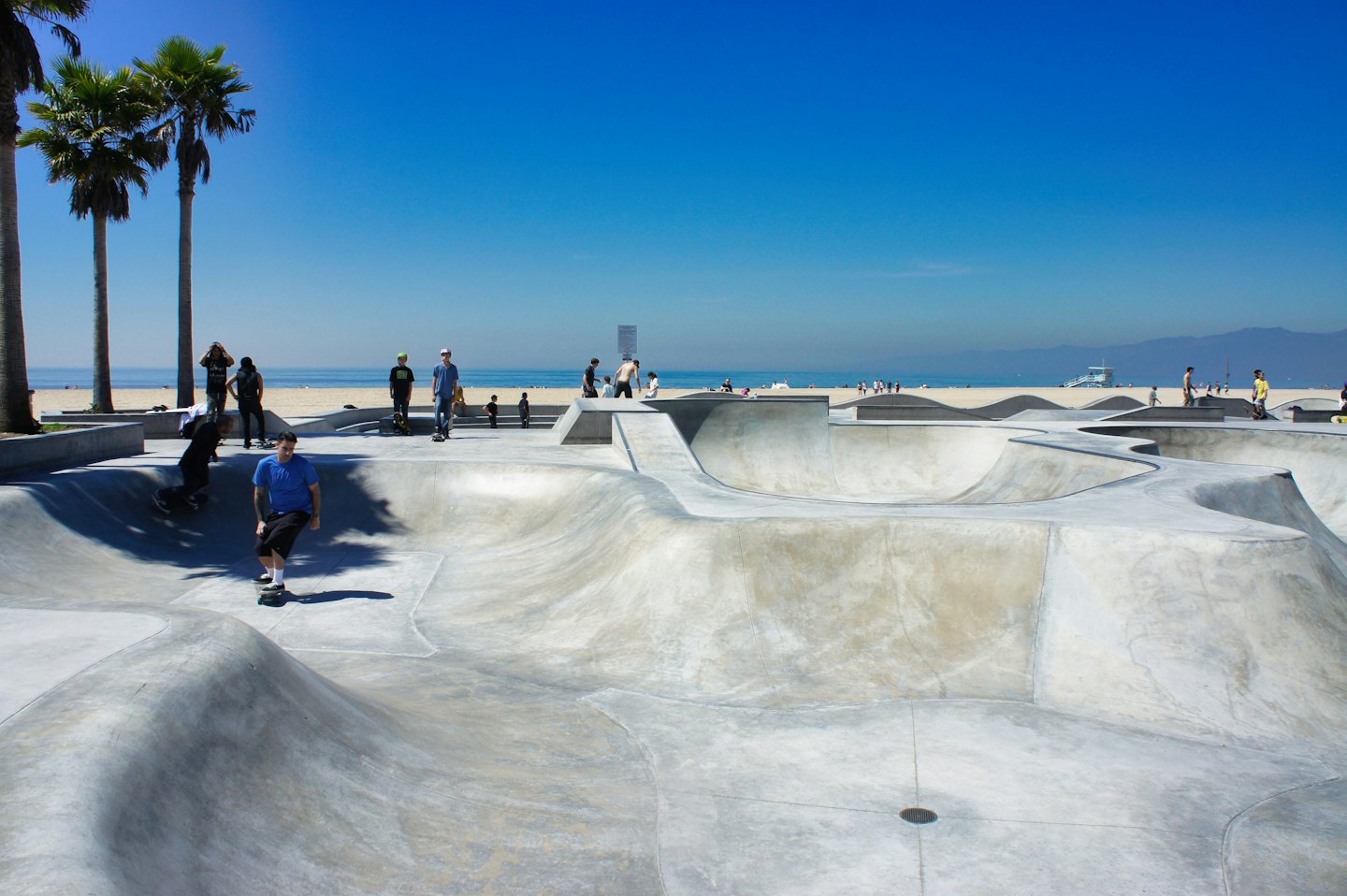 Persone che fanno skateboard in uno skatepark di cemento sulla costa vicino all'oceano.