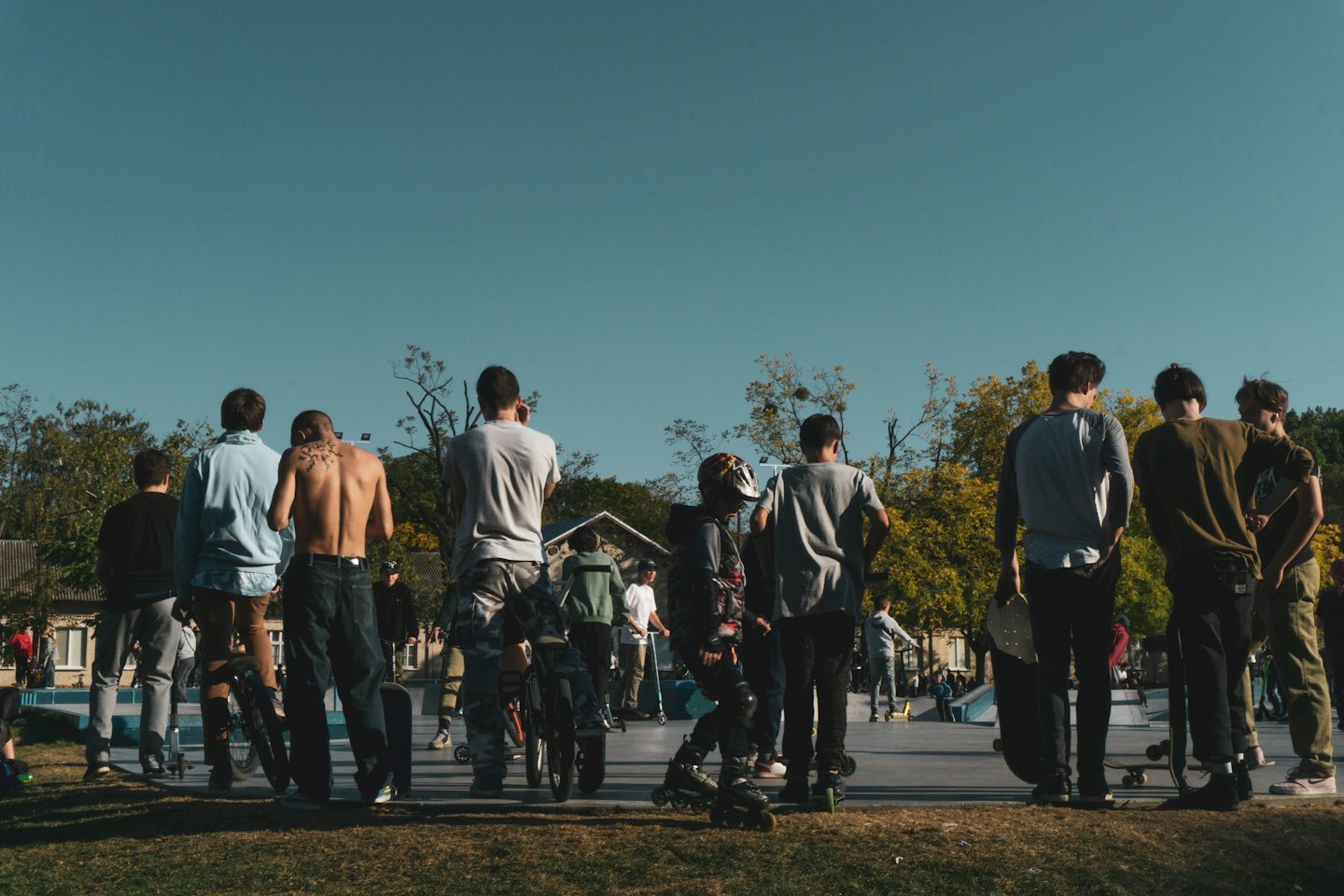 Un gruppo di amici osserva dei pattinatori in un parco di skate all'aperto.